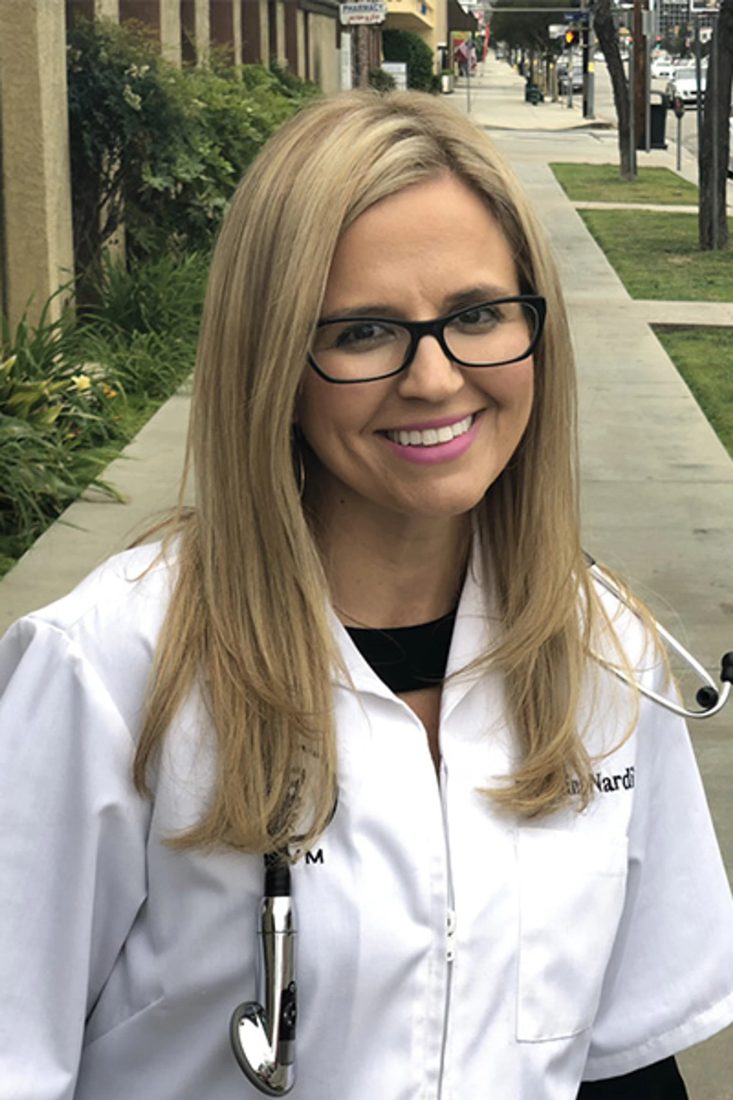 Smiling female veterinarian with glasses and stethoscope outdoors on a sidewalk